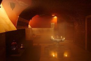 En un Hammam Al Ándalus de Madrid, la sala arqueada y poco iluminada con velas e iluminación suave crea un ambiente cálido y acogedor ideal para el Baño y Masaje Individual MIDRA 30. - ForTwo - Planes para parejas