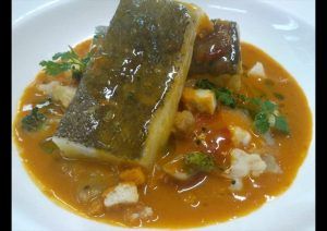 En el Restaurante El Vagón de Beni de Madrid, disfrute de un guiso de pescado con verduras y hierbas servido en una rica salsa de naranja. - ForTwo - Planes para parejas