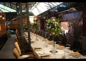 Cene elegantemente en el Restaurante El Vagón de Beni en Madrid, un romántico restaurante de temática tren, con mesas adornadas con centros florales y cristalería brillante. - ForTwo - Planes para parejas