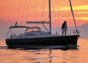 Una pareja se abraza en un yate al atardecer durante su Romántico paseo en barco en la Herradura y Almuñécar, con aguas tranquilas y un cielo anaranjado pintando el horizonte. - ForTwo - Planes para parejas