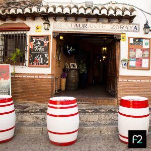 La entrada de Los Jardines de Zoraya rezuma encanto con sus mesas de barril rojas y blancas y su decoración rústica, invitando a vivir el ambiente animado de un espectáculo de flamenco. - ForTwo - Planes para parejas