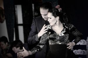 Un hombre y una mujer realizan un expresivo baile flamenco con elegantes atuendos negros, evocando un "Espectáculo de flamenco en los Jardines de Zoraya" privado en un entorno interior íntimo. - ForTwo - Planes para parejas