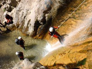 Cuatro personas experimentan la emoción del Barranquismo en Granada - Ruta completa Río Verde mientras uno desciende en rápel por una cascada en el impresionante cañón del Río Verde, mientras otros tres observan desde abajo. - ForTwo - Planes para parejas
