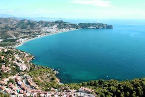 Experimente una impresionante vista aérea de la ciudad costera de la Costa Tropical desde el Vuelo en helicóptero por Costa Tropical Oeste de Granada, que muestra una bahía curva, majestuosas montañas y exuberante vegetación bajo un cielo despejado. - ForTwo - Planes para parejas