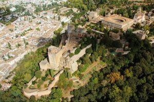 Vista aérea de la Alhambra rodeada de exuberante vegetación, con el paisaje urbano de Granada desplegándose detrás, como se experimenta durante un "Vuelo en helicóptero por Costa Tropical Oeste de Granada. - ForTwo - Planes para parejas