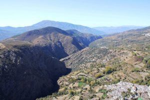 Experimente el Vuelo en helicóptero sobre el Cañón Tajo de los Vados con impresionantes vistas aéreas de su profundo valle, vegetación dispersa y un impresionante paisaje montañoso bajo un cielo azul claro. - ForTwo - Planes para parejas