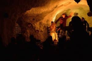 En El Templo del Flamenco - Espectáculo + Menú tapeo, una bailaora actúa con energía en una cueva poco iluminada, cautivando al público con un espectáculo inolvidable. - ForTwo - Planes para parejas