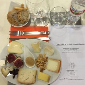 Una mesa puesta para un delicioso "Taller de cata y degustación de quesos artesanos en Barcelona" presenta quesos artesanales, higos, nueces, miel, pan y bebidas. - ForTwo - Planes para parejas