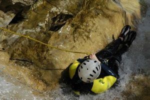 Ataviado con traje de neopreno y casco, un atrevido aventurero desciende en rápel por Río Verde con cuerdas, experimentando el apasionante deporte del "Barranquismo en Granada - Tramo medio de Río Verde". - ForTwo - Planes para parejas