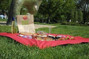 Disfruta de un delicioso "Picnic en Barcelona por sorpresa - Menú Mediterráneo" sobre un manto rojo con vino, baguettes y snacks en un parque para vivir una auténtica experiencia mediterránea. - ForTwo - Planes para parejas