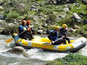 Cuatro aventureros navegando por el Rafting en Granada - Canal de aguas bravas en una balsa neumática amarilla, equipados con cascos y chalecos salvavidas, encarnan el espíritu de aventura. - ForTwo - Planes para parejas