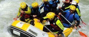 Aventureros con cascos y trajes de neopreno conquistan las aguas bravas de Granada haciendo rafting en una barca neumática amarilla con la experiencia Rafting en Granada - Canal de aguas bravas. - ForTwo - Planes para parejas