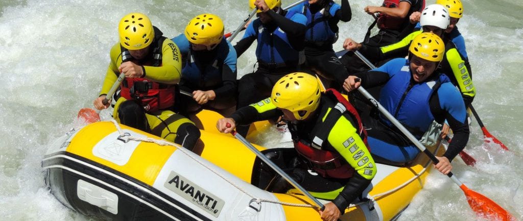 Aventureros con cascos y trajes de neopreno conquistan las aguas bravas de Granada haciendo rafting en una barca neumática amarilla con la experiencia Rafting en Granada - Canal de aguas bravas. - ForTwo - Planes para parejas
