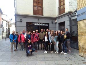 Un grupo de personas posando alegremente frente a un edificio con el cartel de La Moderna captura la esencia vibrante del Sacromonte durante el Tour por el Albaicín y Sacromonte de FeelTheCity. - ForTwo - Planes para parejas