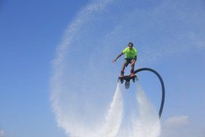 Utilizando la experiencia *Vuela sobre el agua en Hoverboard o Flyboard en Barcelona*, una persona crea hábilmente un patrón circular de rociado sobre las aguas cristalinas. - ForTwo - Planes para parejas