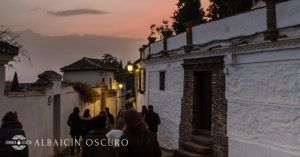Los turistas se embarcan en el recorrido "Conspiración en el Albaicín Granada", paseando por calles estrechas al atardecer, sus pasos resuenan a través de edificios blancos bajo un cielo brumoso como si fueran parte de una conspiración silenciosa con la historia. - ForTwo - Planes para parejas