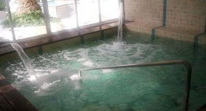 La piscina cubierta, inspirada en la Habitación doble y circuito de aguas saludables del Balneario de Lanjarón (Granada), cuenta con chorros de agua y pasamanos metálicos, todo ello elegantemente enmarcado por paredes de azulejos y tarimas de madera. - ForTwo - Planes para parejas