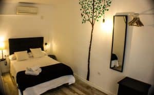 Habitación con encanto en el Apartamento para 2 en el centro de Granada. Cuenta con cama, vinilo decorativo de árbol, espejo e iluminación acogedora. El aire acondicionado de pared está convenientemente ubicado sobre la cama. - ForTwo - Planes para parejas
