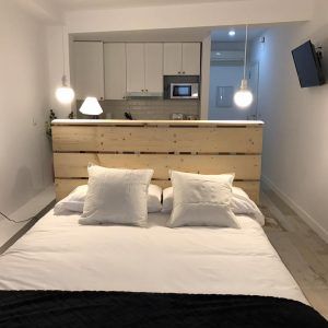 Apartamento para 2 en el centro de Granada: moderno estudio con cama elegante, divisor de madera, luces colgantes, área de cocina y TV de pared. - ForTwo - Planes para parejas