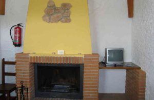 Datos del producto: Una noche en cueva romántica de turismo rural (Guadix). Frase reescrita: Una noche en cueva romántica de turismo rural (Guadix) ofrece un refugio rústico con una chimenea de ladrillo amarillo que crea el ambiente perfecto, un pequeño televisor en el estante derecho y un extintor en la pared izquierda. Disfrute de una encantadora intimidad. - ForTwo - Planes para parejas