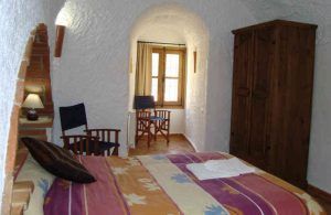 Experimente un acogedor dormitorio con cama doble, armario, sillas y más en una habitación arqueada durante "Una noche en cueva romántica de turismo rural (Guadix)", perfecta para quienes buscan el encanto del turismo rural. - ForTwo - Planes para parejas