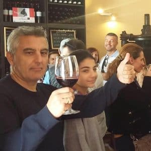En un ambiente de grupo animado, un hombre que disfruta de la "Visita guiada a Bodega del Nero con tren turístico y degustación de 3 vinos" levanta su copa de vino tinto y levanta el pulgar. - ForTwo - Planes para parejas