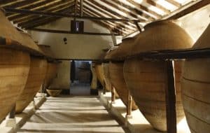 Grandes vasijas de barro en una sala rústica con vigas de madera que recuerda a la Bodega del Nero realzan el encanto de una bodega tradicional, perfecta para una deliciosa "Visita guiada a Bodega del Nero con tren turístico y degustación de 3 vinos". - ForTwo - Planes para parejas