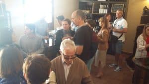 En un acogedor café de ambiente cálido, la gente socializa, algunos sosteniendo bebidas del paquete de visita a la Bodega del Nero con recorrido en tren y degustación de 3 vinos. - ForTwo - Planes para parejas