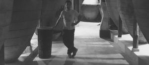 En la Bodega del Nero, con poca luz, un hombre se encuentra entre grandes barriles de madera, abrazando la atmósfera de esta célebre bodega durante su "Visita guiada a Bodega del Nero con tren turístico y degustación de 3 vinos. - ForTwo - Planes para parejas