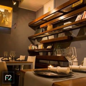 Menú Sabores en Restaurante Ruta del Azafrán, ubicado frente a la Alhambra, cuenta con modernos estantes de madera, mesas puestas e iluminación tenue para crear un ambiente acogedor para los comensales. - ForTwo - Planes para parejas