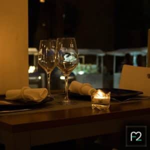 Una cena romántica con copas de vino, velas y servilletas adorna la mesa tenuemente iluminada, capturando el encanto de la Alhambra. Realce su velada en el Restaurante Ruta del Azafrán con el exquisito Menú Sabores para una experiencia inolvidable. - ForTwo - Planes para parejas