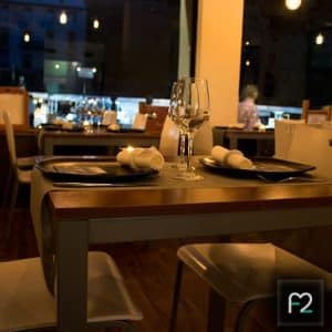 El Menú Sabores en Restaurante Ruta del Azafrán, presentado en una elegante mesa para dos con copas de vino y servilletas, se exhibe en un ambiente de suave iluminación. - ForTwo - Planes para parejas