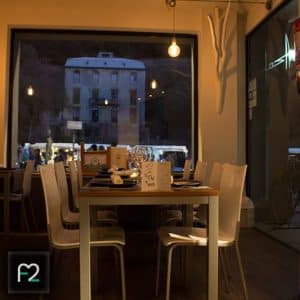 Experimente el acogedor ambiente del Restaurante Ruta del Azafrán, con una mesa puesta bajo una iluminación tenue y una impresionante vista de la Alhambra iluminada. Disfrute del exquisito Menú Sabores mientras se sumerge en este ambiente acogedor. - ForTwo - Planes para parejas