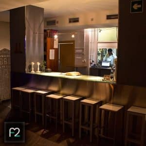El Restaurante Ruta del Azafrán cuenta con una barra con iluminación tenue, una barra luminosa, decoración moderna y taburetes acogedores. Un experto prepara bebidas en este evocador lugar, realzando las vistas de la Alhambra y complementando el exquisito Menú Sabores del Restaurante Ruta del Azafrán frente a la Alhambra. - ForTwo - Planes para parejas