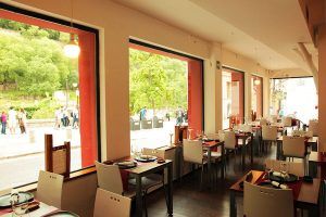 El Restaurante Ruta del Azafrán ofrece una experiencia gastronómica tranquila con amplios ventanales que dejan ver la vegetación y las vistas a la calle. Elegantes mesas le esperan para servirle el Menú Sabores, inspirado en la rica gastronomía local cerca de la majestuosa Alhambra. - ForTwo - Planes para parejas