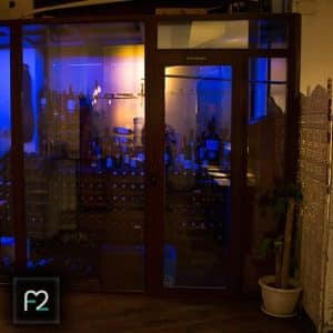 La bodega tenuemente iluminada del Restaurante Ruta del Azafrán, con botellas en los estantes e iluminación ambiental azul, te invita a explorar el Menú Sabores en Restaurante Ruta del Azafrán frente a la Alhambra mientras imaginas la majestuosidad de la cercana Alhambra. - ForTwo - Planes para parejas