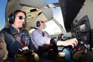 Dos pilotos con auriculares ajustan los controles en la cabina de un pequeño avión, navegando con gracia por los cielos en un vuelo en avión en Barcelona. - ForTwo - Planes para parejas