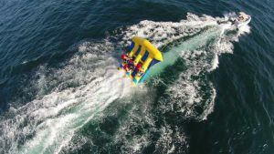 Un grupo es arrastrado por un Flyfish inflable amarillo, creando una estela salpicada sobre las olas del océano, mientras disfrutan "Salta por los aires sobre el mar practicando el Flyfish en Barcelona. - ForTwo - Planes para parejas