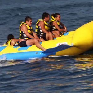 Cuatro personas con chalecos salvavidas recorren Salta por los aires sobre el mar practicando el Flyfish en Barcelona, sumergiéndose en las vibrantes aguas y el sol. - ForTwo - Planes para parejas