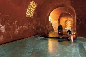 En Hammam Al Ándalus Granada Baños Árabes, uno se relaja en una lujosa piscina cubierta con arcos intrincados, iluminación cálida y una decoración elegante que evoca los tradicionales Baños Árabes. - ForTwo - Planes para parejas