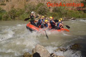Disfruta del rafting en grupo en Rafting en el Río Genil - Aguas Bravas, luchando contra las corrientes y remando vigorosamente en una balsa inflable bajo un cielo soleado. - ForTwo - Planes para parejas