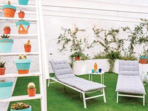 Relájese en el patio al aire libre de Le Patio Spa, que cuenta con dos tumbonas grises, plantas en macetas en una escalera y una pequeña mesa con vasos de colores, ideal después de disfrutar del Ritual Básico con exfoliación. - ForTwo - Planes para parejas