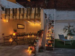 Disfrute de un acogedor patio decorado con guirnaldas de luces y velas, con mesa, sillas, plantas exuberantes y una escalera que conduce a tumbonas en la zona de césped. Es el entorno perfecto para su Ritual Básico con exfoliación después de sumergirse en el ambiente sereno de Le Patio Spa. - ForTwo - Planes para parejas