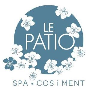Texto sobre un círculo azul con flores blancas: "LE PATIO SPA" centrado; "SPA • COS I MENT" debajo. Disfrute del Ritual Básico con exfoliación en Le Patio Spa para una relajación total. - ForTwo - Planes para parejas