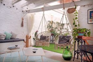Relájese en el acogedor patio de Le Patio Spa después de su Ritual Básico con exfoliación, rodeado de sillas colgantes, mesas pequeñas, plantas exuberantes y paredes de ladrillo blanco bajo un techo parcialmente cubierto. - ForTwo - Planes para parejas