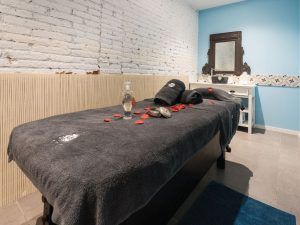 En la tranquila sala de paredes azul claro, le espera una camilla de masajes adornada con toallas negras, pétalos de rosa y artículos de spa. Disfrute del Ritual Básico con Exfoliación en Le Patio Spa para rejuvenecerse y relajarse. - ForTwo - Planes para parejas