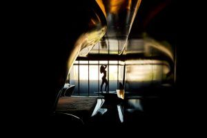 Silueta de una persona estirada junto a grandes ventanales en el elegante y moderno interior de un local de Málaga con paredes curvas durante una Sesión fotográfica boudoir en pareja Málaga. - ForTwo - Planes para parejas