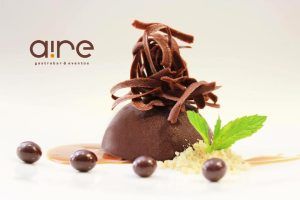 Disfrute de un postre exquisito en Aire Gastrobar - Cocina mediterránea de autor, con ricas virutas de chocolate, cremosa salsa de caramelo, hojas de menta fresca y bombones. Una armoniosa combinación de dulzura y encanto mediterráneo deleitará su paladar. - ForTwo - Planes para parejas