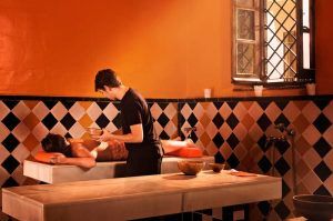 En Málaga, una persona disfruta de la tranquilidad con un masaje relajante en el Hammam Spa de paredes naranjas, acentuado por azulejos con diseño de diamantes, que abrazan la serenidad del Baño sencillo en el Hammam Spa de Málaga. - ForTwo - Planes para parejas
