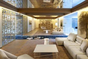 Una moderna sala de estar con sofás beige, paneles decorativos y paredes de cristal crea un espacio abierto y aireado que recuerda a una lujosa suite del Mandarin Hotel en Barcelona SPA. - ForTwo - Planes para parejas